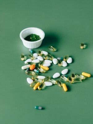 Assorted pills and herbal remedies displayed on green surface, emphasizing natural health concepts.