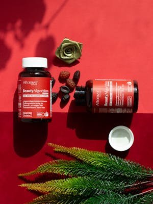 Colorful flat lay of beauty supplements and decor on vibrant red background.